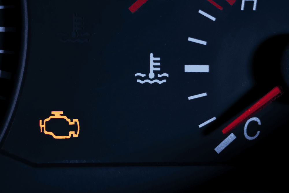 Check engine light, auto repair in Naperville, IL at Clark’s Car Care. Image of an illuminated check engine warning beside the engine temperature gauge on a vehicle dashboard.